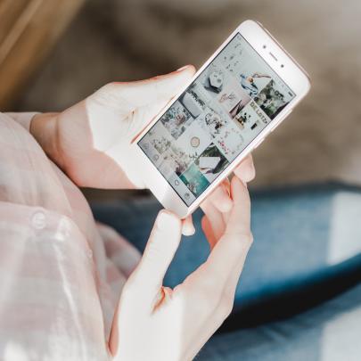 woman looking down at her phone showing various images on screen