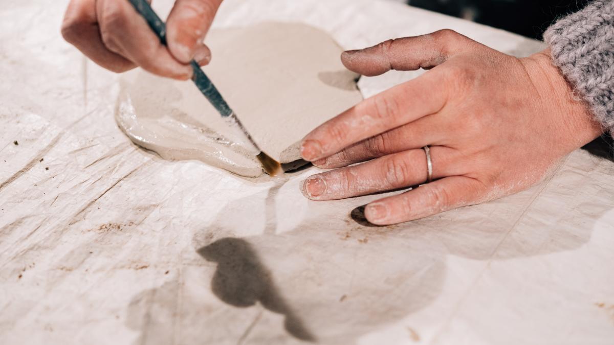 Hands working on flat rolled clay